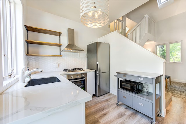1121 Lashbrook Dr, Houston, TX 77077 - kitchen with open shelves, wall chimney range hood, appliances with stainless steel finishes, decorative backsplash, and light wood-type flooring