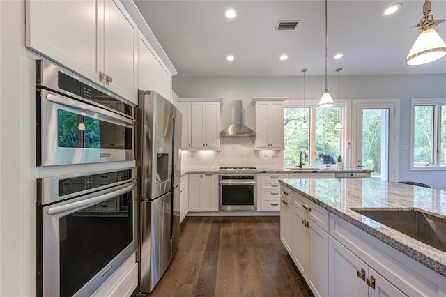 1121 Lashbrook Dr, Houston, TX 77077 - kitchen with wall chimney range hood, stainless steel appliances, white cabinetry, dark wood-type flooring, and hanging light fixtures