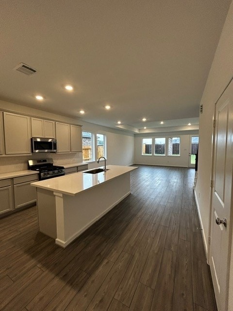 1127 Buffalo Run, Tomball, TX 77375 - kitchen with stainless steel microwave, gas stove, dark wood-type flooring, a kitchen island with sink, and open floor plan