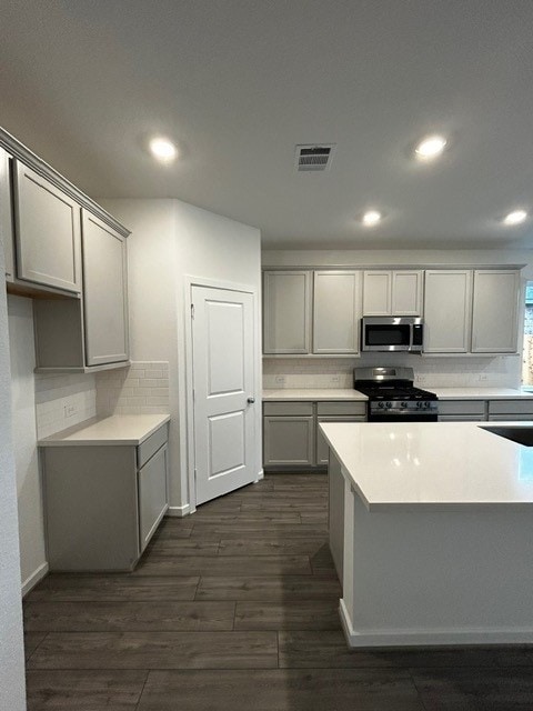 1127 Buffalo Run, Tomball, TX 77375 - kitchen featuring stainless steel microwave, black range with gas stovetop, gray cabinets, and recessed lighting
