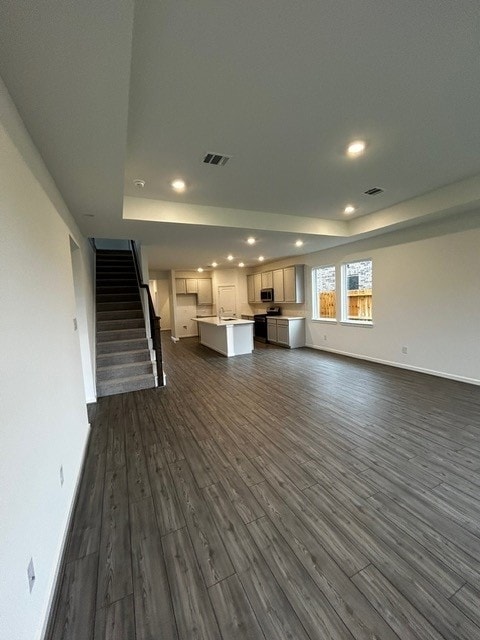 1127 Buffalo Run, Tomball, TX 77375 - unfurnished living room featuring recessed lighting, a tray ceiling, dark wood finished floors, and stairs