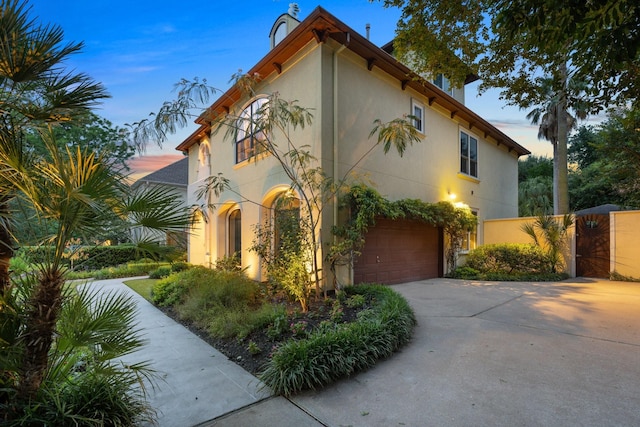 38 Hackberry Ln, Houston, TX 77027 - view of front facade with an attached garage, stucco siding, concrete driveway, and a gate