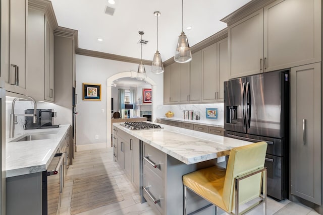 38 Hackberry Ln, Houston, TX 77027 - kitchen with appliances with stainless steel finishes, a center island, backsplash, arched walkways, and gray cabinetry