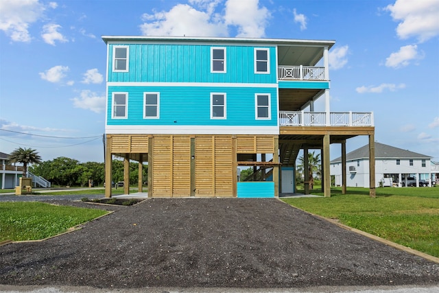 210 Galveston St, Crystal Beach, TX 77650 - raised beach house featuring a carport, driveway, a balcony, a front yard, and board and batten siding
