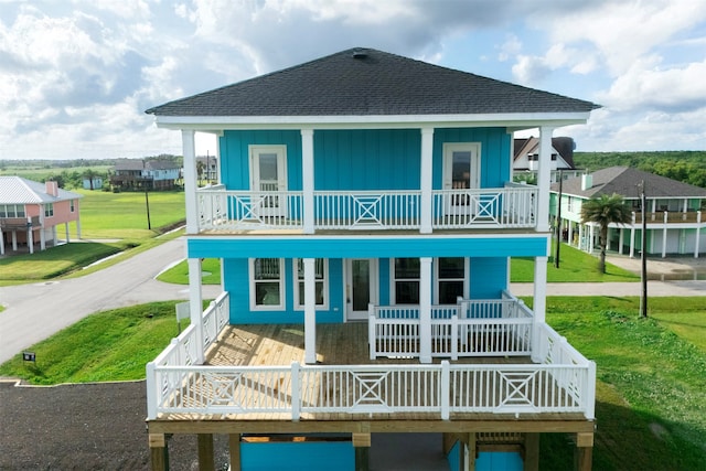 210 Galveston St, Crystal Beach, TX 77650 - back of property with covered porch, roof with shingles, a balcony, board and batten siding, and a yard
