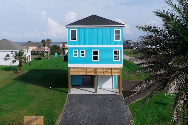 210 Galveston St, Crystal Beach, TX 77650 - view of front facade with driveway, board and batten siding, a front yard, a garage, and a carport