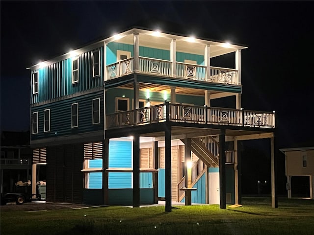 210 Galveston St, Crystal Beach, TX 77650 - back of house at twilight featuring board and batten siding, a balcony, and stairs