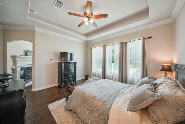 5924 Oak Leaf Ct, Conroe, TX 77304 - bedroom featuring a raised ceiling, a glass covered fireplace, wood finished floors, crown molding, and a ceiling fan