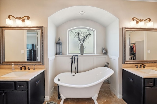 5924 Oak Leaf Ct, Conroe, TX 77304 - bathroom with two vanities, wainscoting, a freestanding tub, a walk in closet, and a decorative wall
