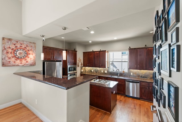 5122 Lillian St, Houston, TX 77007 - kitchen with stainless steel appliances, a peninsula, light wood-type flooring, decorative backsplash, and pendant lighting