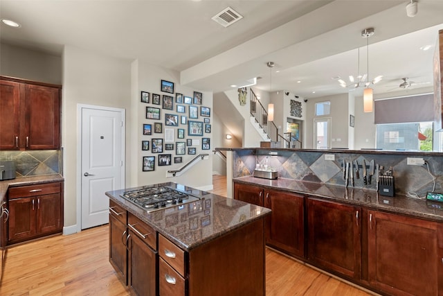 5122 Lillian St, Houston, TX 77007 - kitchen featuring stainless steel gas cooktop, light wood-style floors, tasteful backsplash, dark stone countertops, and pendant lighting