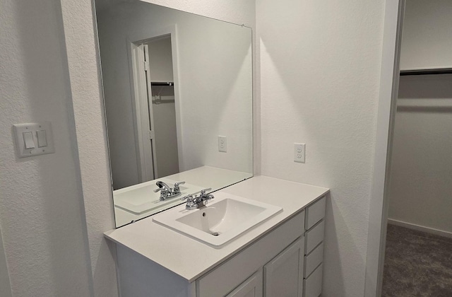3005 Blue Gem Ct, Katy, TX 77493 - bathroom with vanity, a walk in closet, and a textured wall