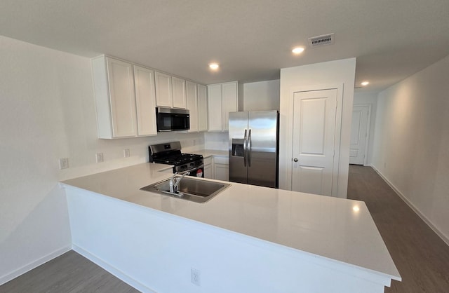 3005 Blue Gem Ct, Katy, TX 77493 - kitchen with stainless steel appliances, light countertops, a peninsula, dark wood finished floors, and white cabinets
