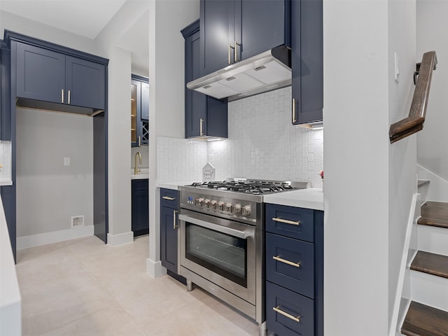 825 Paul Quinn St Unit E, Houston, TX 77091 - kitchen with stainless steel stove, under cabinet range hood, blue cabinetry, light countertops, and decorative backsplash