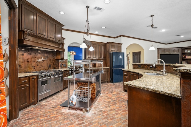 2790 Derby Ln, Madisonville, TX 77864 - kitchen featuring double oven range, arched walkways, freestanding refrigerator, a kitchen island with sink, and decorative backsplash