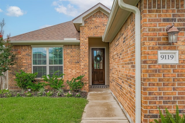 9119 Anna St, Needville, TX 77461 - doorway to property with brick siding, a shingled roof, and a yard