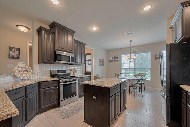 9119 Anna St, Needville, TX 77461 - kitchen featuring stainless steel appliances, backsplash, dark brown cabinets, a chandelier, and pendant lighting