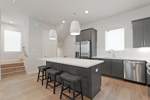 709 Sienna Palm Ln, Houston, TX 77008 - kitchen with appliances with stainless steel finishes, light wood-style floors, backsplash, a kitchen bar, and light countertops