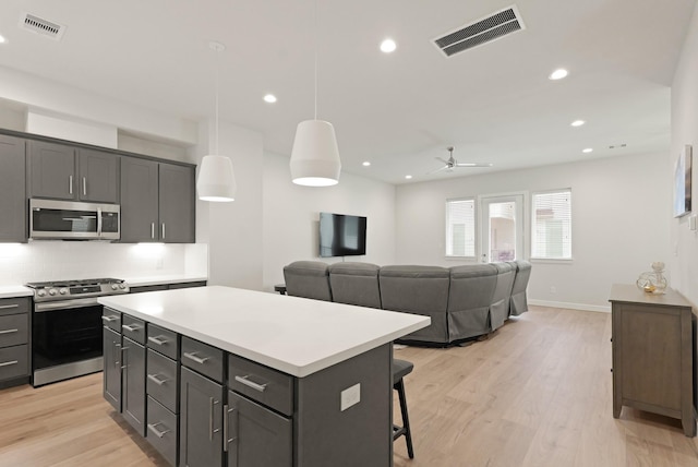 709 Sienna Palm Ln, Houston, TX 77008 - kitchen with stainless steel appliances, a center island, light countertops, backsplash, and light wood-style floors