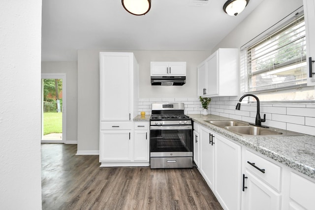 9611 Bertwood St, Houston, TX 77016 - kitchen with stainless steel gas range, under cabinet range hood, dark wood finished floors, and backsplash