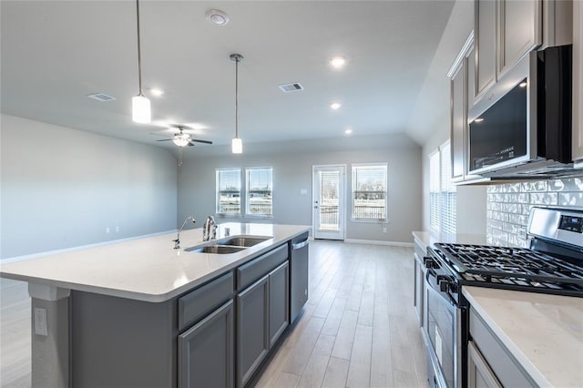 1202 Oak Barrel Run, Richmond, TX 77406 - kitchen featuring appliances with stainless steel finishes, gray cabinetry, healthy amount of natural light, light wood finished floors, and recessed lighting