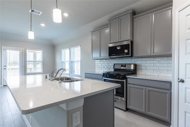 1202 Oak Barrel Run, Richmond, TX 77406 - kitchen featuring gray cabinets, appliances with stainless steel finishes, a kitchen island with sink, backsplash, and decorative light fixtures