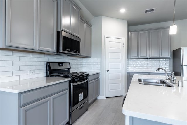 1202 Oak Barrel Run, Richmond, TX 77406 - kitchen featuring appliances with stainless steel finishes, gray cabinetry, light wood-type flooring, tasteful backsplash, and recessed lighting