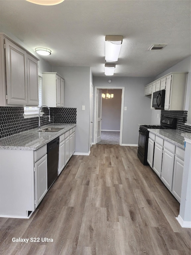 14119 Falling Elm Ln, Houston, TX 77015 - kitchen with black appliances, backsplash, light wood-type flooring, and light stone counters