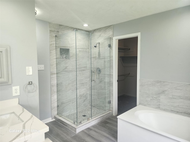 14119 Falling Elm Ln, Houston, TX 77015 - bathroom featuring a stall shower, a bath, a walk in closet, wood finished floors, and vanity