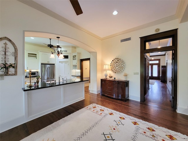1406 Key St, Brenham, TX 77833 - kitchen featuring stainless steel appliances, ceiling fan, dark countertops, dark wood finished floors, and ornamental molding