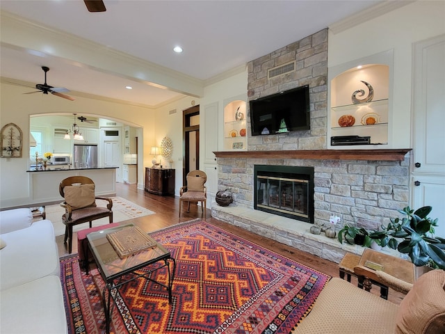 1406 Key St, Brenham, TX 77833 - living room featuring a ceiling fan, ornamental molding, wood finished floors, a fireplace, and arched walkways