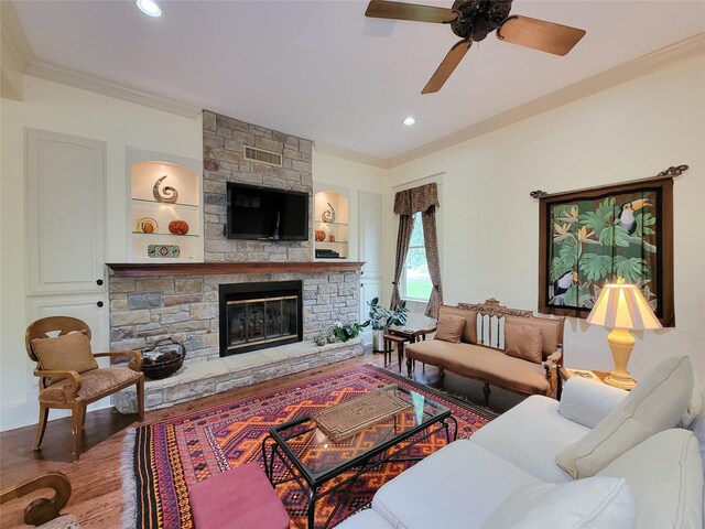1406 Key St, Brenham, TX 77833 - living room with crown molding, a stone fireplace, a ceiling fan, wood finished floors, and recessed lighting