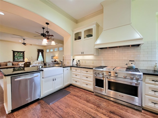 1406 Key St, Brenham, TX 77833 - kitchen featuring appliances with stainless steel finishes, custom range hood, dark countertops, crown molding, and a peninsula
