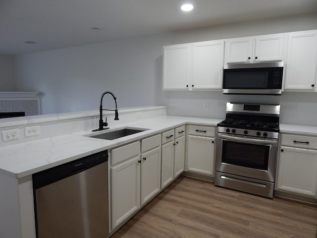 16861 Greenhouse St, Conroe, TX 77385 - kitchen with stainless steel appliances, a peninsula, dark wood-style flooring, white cabinets, and light stone counters