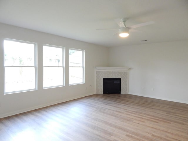 16861 Greenhouse St, Conroe, TX 77385 - unfurnished living room featuring light wood-type flooring, a tiled fireplace, and ceiling fan