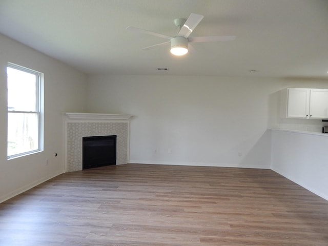 16861 Greenhouse St, Conroe, TX 77385 - unfurnished living room featuring a tile fireplace, light wood-type flooring, and ceiling fan