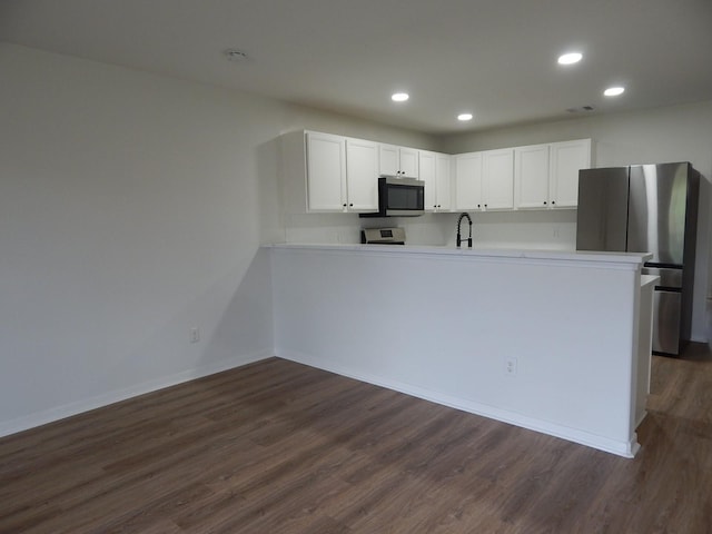 16861 Greenhouse St, Conroe, TX 77385 - kitchen featuring appliances with stainless steel finishes, dark wood-style flooring, a peninsula, white cabinetry, and recessed lighting