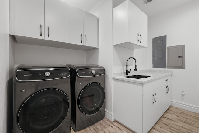 43919 Austin Branch Rd, Hempstead, TX 77445 - laundry room with electric panel, washing machine and clothes dryer, light wood-style floors, and cabinet space