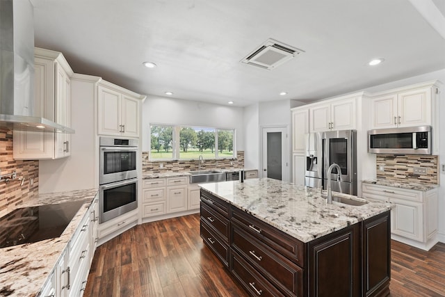43919 Austin Branch Rd, Hempstead, TX 77445 - kitchen featuring appliances with stainless steel finishes, wall chimney range hood, backsplash, white cabinets, and recessed lighting