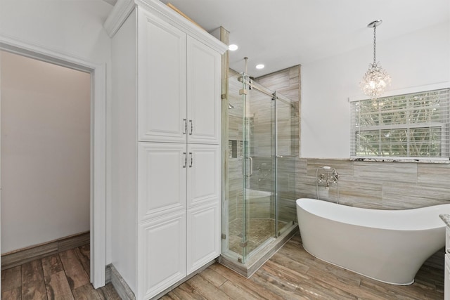43919 Austin Branch Rd, Hempstead, TX 77445 - full bath featuring a stall shower, a freestanding bath, tile walls, wood finished floors, and a chandelier
