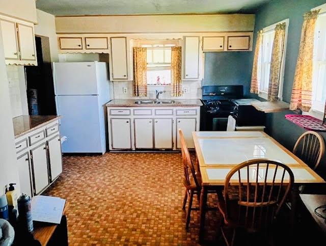 17066 State Highway 36 S, Somerville, TX 77879 - kitchen featuring freestanding refrigerator, gas stove, light countertops, and white cabinets