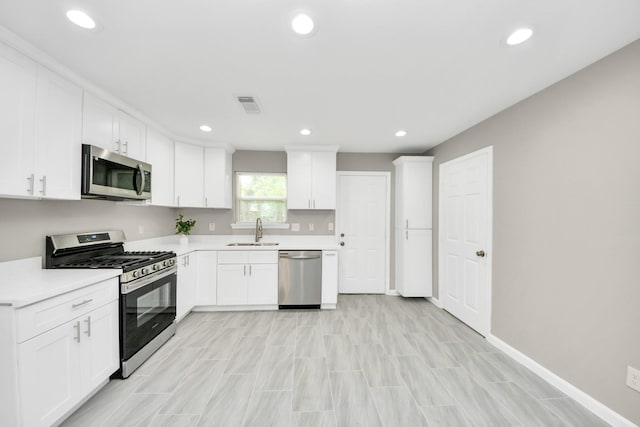 5722 Beldart St, Houston, TX 77033 - kitchen featuring appliances with stainless steel finishes, light countertops, white cabinetry, and recessed lighting