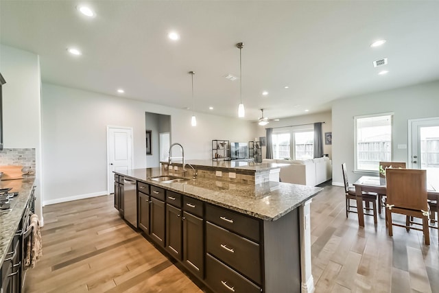 1638 Dominion Heights Ln, Katy, TX 77423 - kitchen featuring light wood-style flooring, light stone counters, backsplash, open floor plan, and recessed lighting