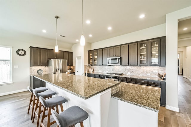 1638 Dominion Heights Ln, Katy, TX 77423 - kitchen featuring appliances with stainless steel finishes, light wood-type flooring, dark brown cabinets, a kitchen breakfast bar, and decorative backsplash