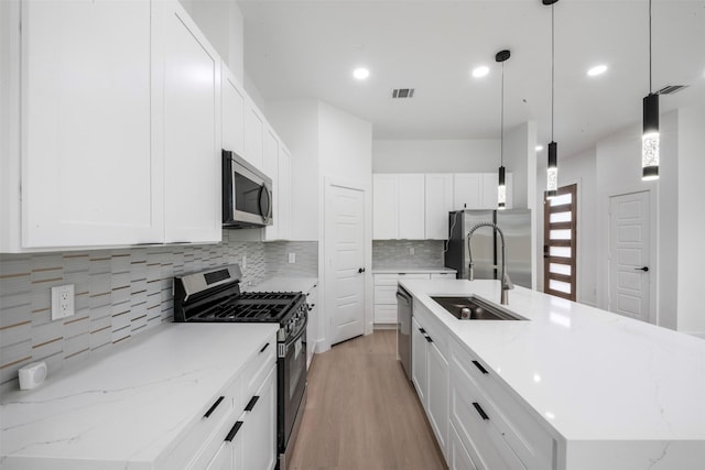 6815 Paris St, Houston, TX 77021 - kitchen with appliances with stainless steel finishes, a spacious island, tasteful backsplash, light wood-style flooring, and white cabinetry
