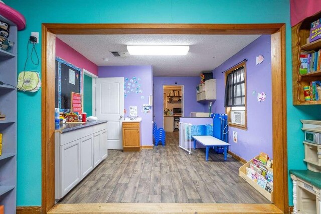 402 W Converse St, Weimar, TX 78962 - kitchen with light wood-type flooring, white cabinetry, a textured ceiling, and cooling unit