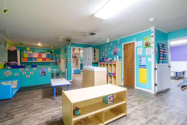 402 W Converse St, Weimar, TX 78962 - playroom featuring a textured ceiling, crown molding, wood finished floors, and ceiling fan