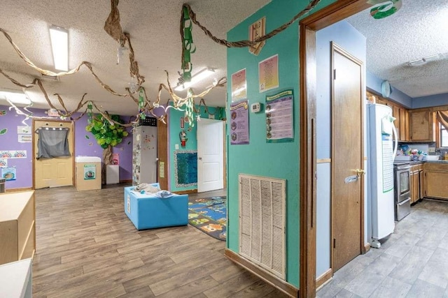 402 W Converse St, Weimar, TX 78962 - below grade area featuring a textured ceiling, freestanding refrigerator, and light wood-style floors