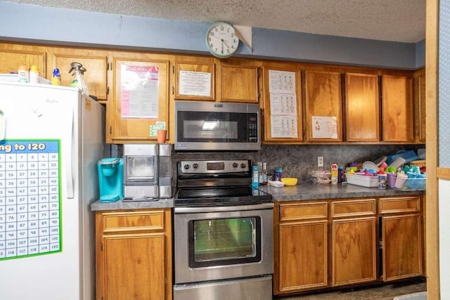 402 W Converse St, Weimar, TX 78962 - kitchen featuring appliances with stainless steel finishes, brown cabinets, and a textured ceiling