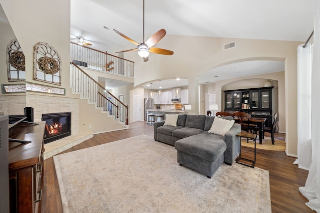 19610 Blushing Meadow Dr, Cypress, TX 77433 - living area with arched walkways, a stone fireplace, ceiling fan, dark wood-type flooring, and high vaulted ceiling